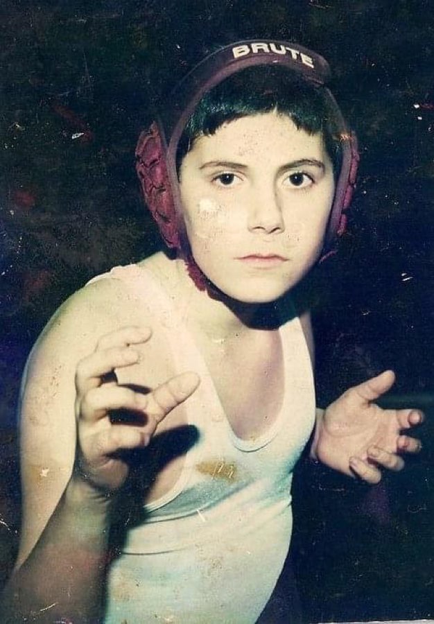 Daniel Reichenbach as a child wearing wrestling headgear and posing in a wrestling stance