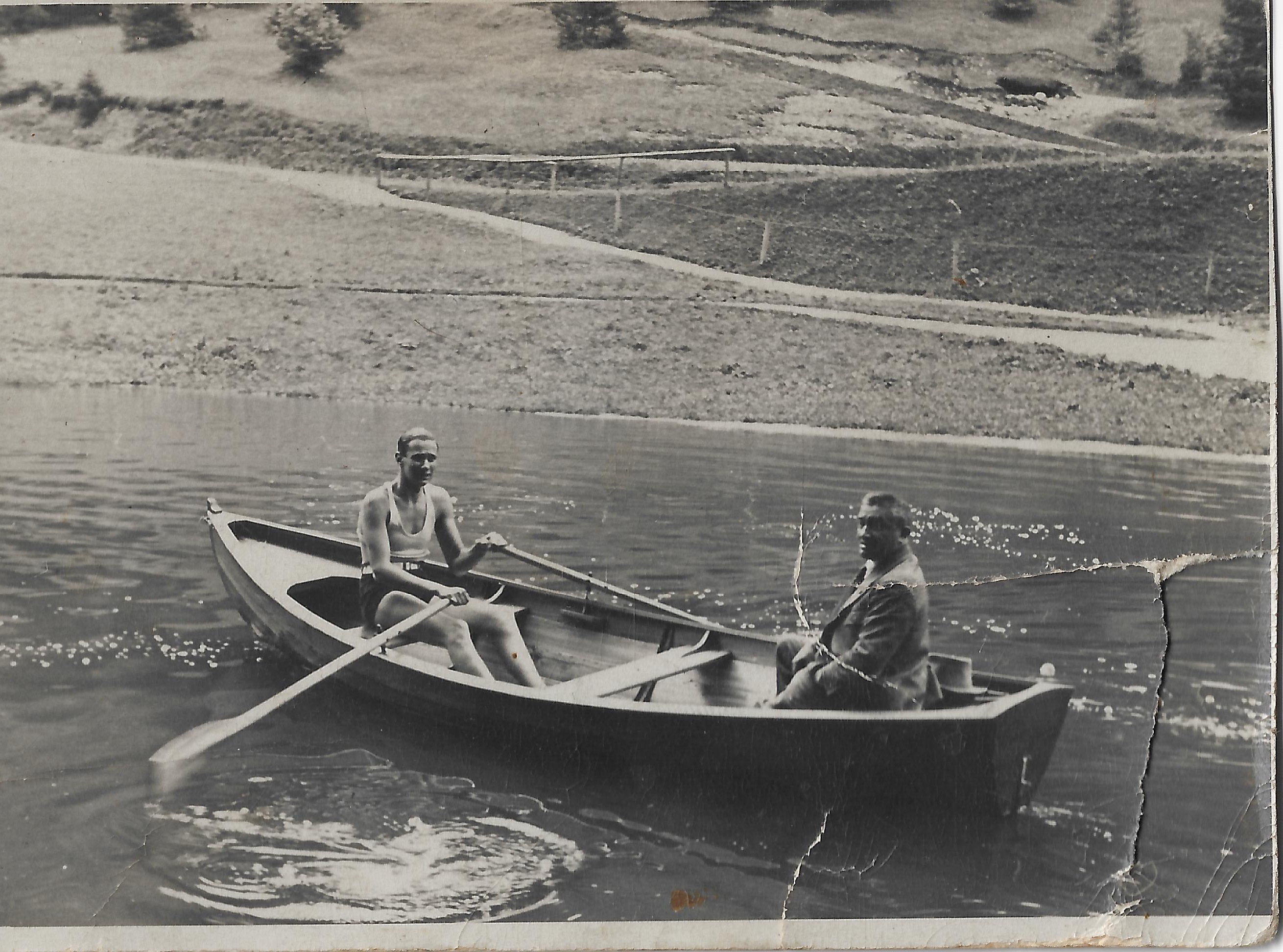 Two men in a rowboat on a mountain lake, Paul Reichenbach seated in jacket and tie